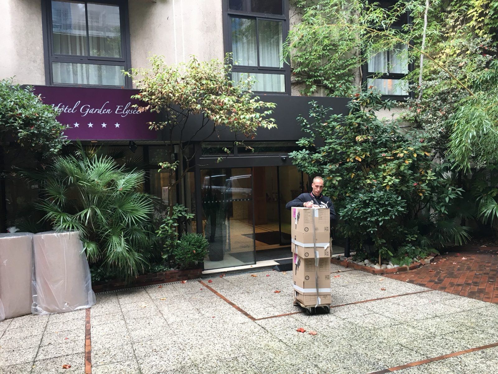 Déménageur avec un diable chargé de cartons devant un hôtel parisien