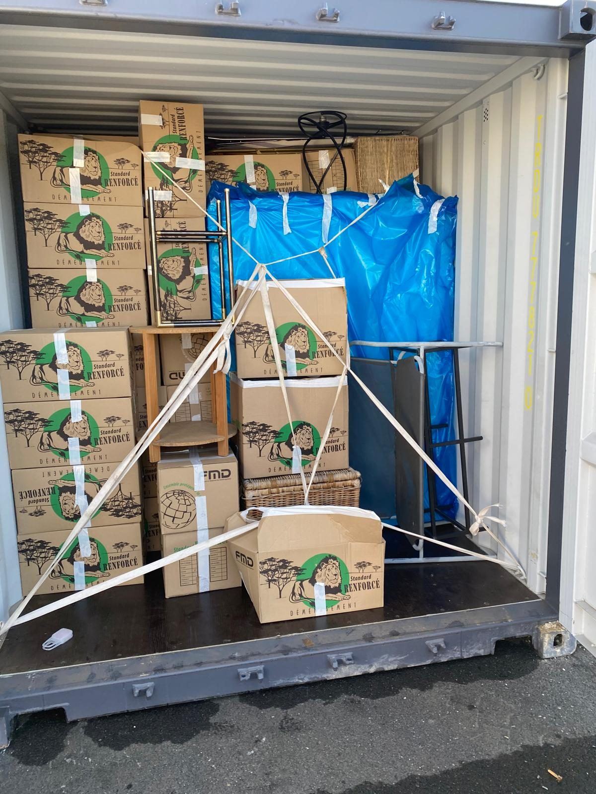 Conteneur chargé de cartons et de meubles, sanglé